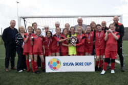 Millbrook Primary in all red kits. all players and coaches together celebrating their win with the trophy