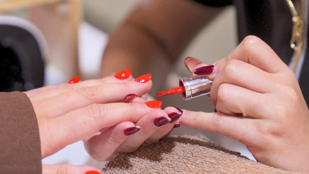 Applying red nail polish on hands